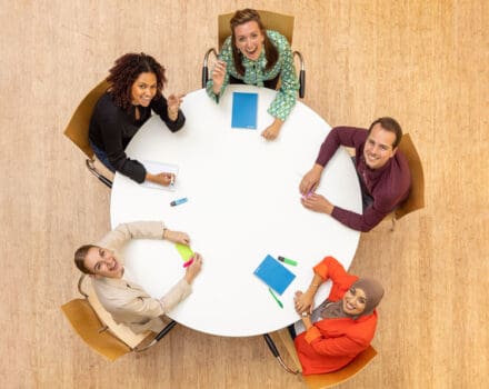 Collega's zitten samen aan tafel en lachen