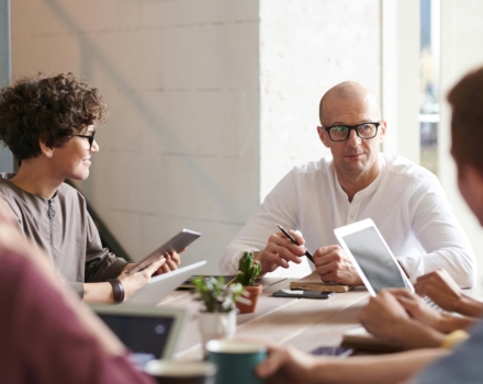 mensen vergaderen aan een houten tafel met laptops daarop