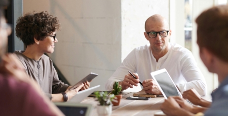 mensen vergaderen aan een houten tafel met laptops daarop