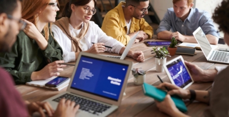 collega's zitten aan een bureau en overleggen kijkend naar een presentatie