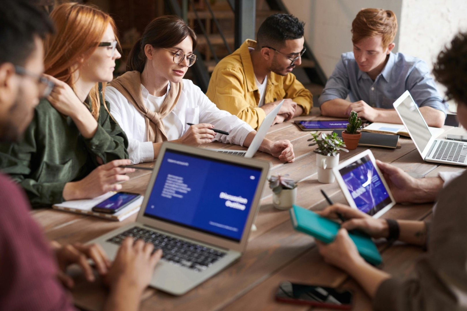 collega's zitten aan een bureau en overleggen kijkend naar een presentatie