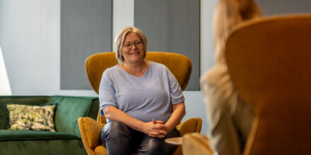 twee collega's praten met elkaar zittend op bruine stoelen