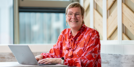 Collega werkt met een brede glimlach achter een laptop
