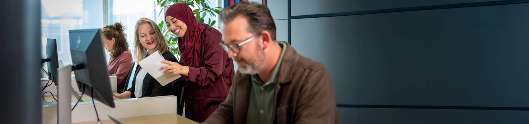 Vier collega's werken achter hun bureau op kantoor