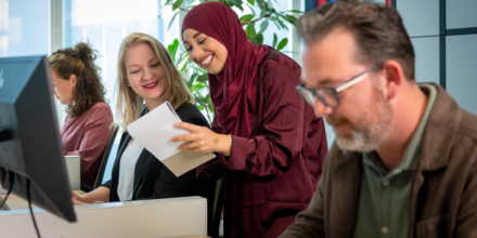 Vier collega's werken achter hun bureau op kantoor