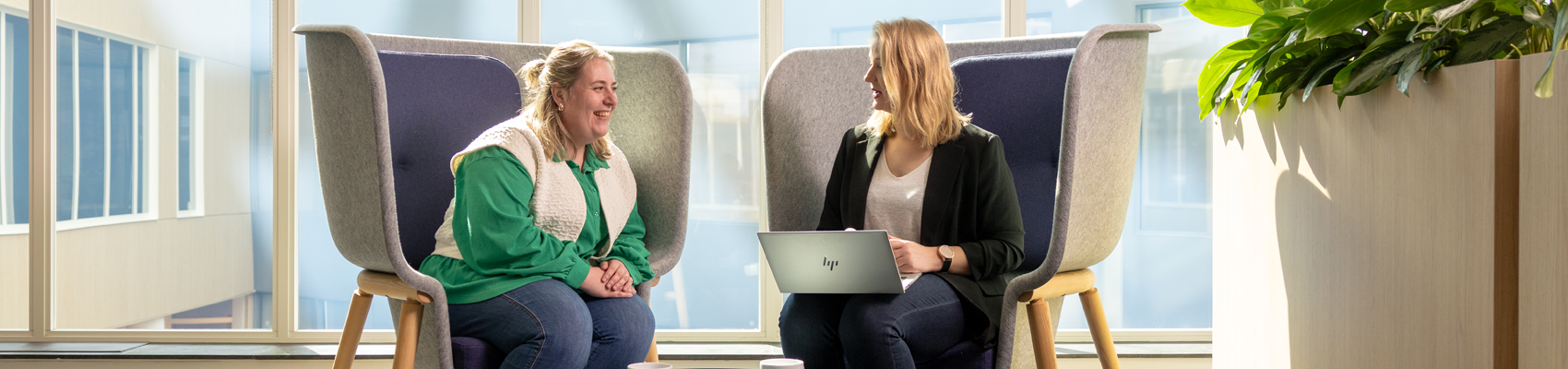 Twee collega's zijn in gesprek met elkaar achter één laptop
