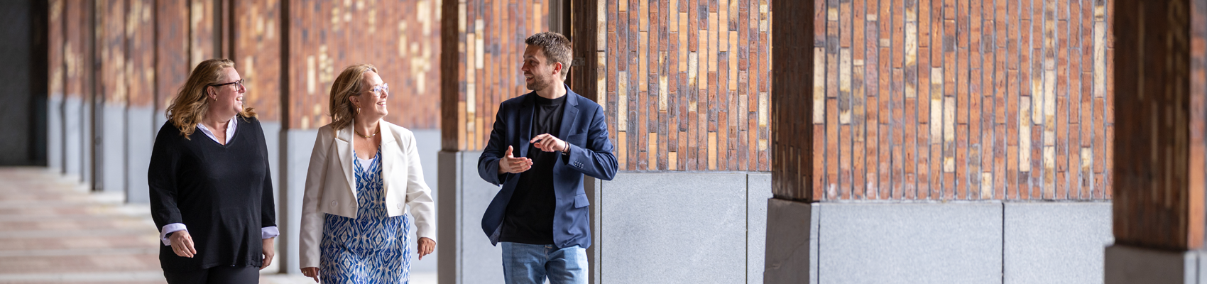 Drie collega's wandelen buiten en zijn in gesprek