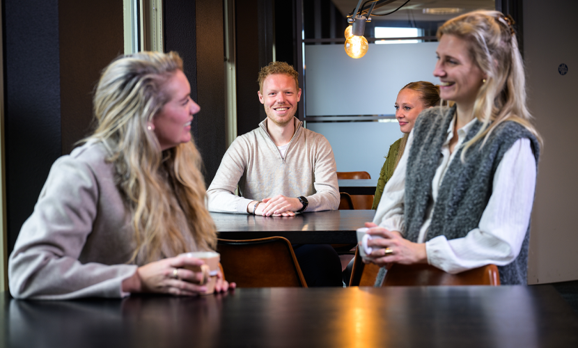 Vier medewerkers zijn met elkaar in gesprek