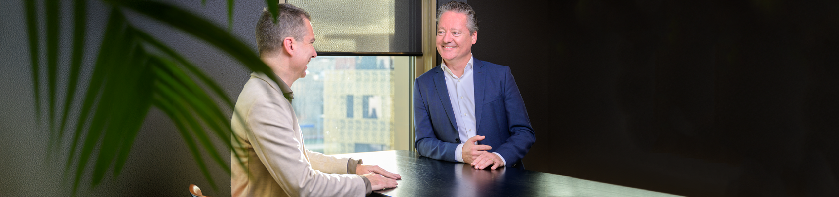 Banner 1700×400 twee collega’s zijn met elkaar in gesprek aan tafel