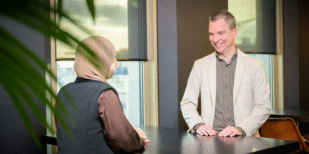 Banner 800×500 mobiel twee collega’s zijn met elkaar in gesprek aan tafel