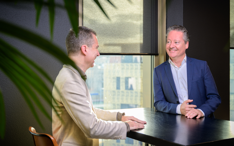 Banner 800×500 mobile twee collega’s zijn met elkaar in gesprek aan tafel