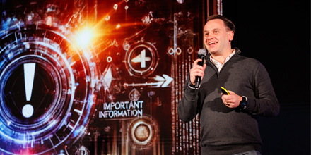 Man op podium met microfoon en presentatie achtergrond