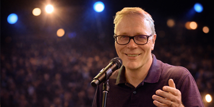 Man op podium met publiek op achtergrond