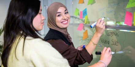 Twee collega's zijn aan het brainstormen met sticky notes