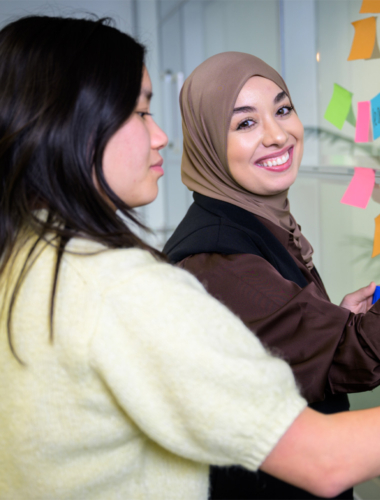 Twee collega's zijn aan het brainstormen met sticky notes