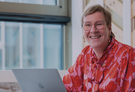 Medewerker lacht en werkt achter laptop