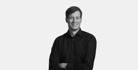Black-and-white portrait photo of a smiling man with his arms crossed.