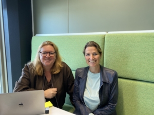 Twee collega's zijn samen aan het werk en lachen in de camera
