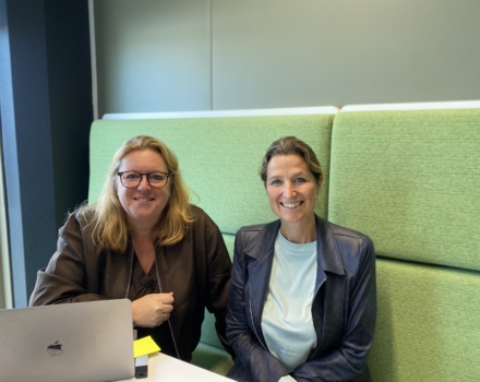 Twee collega's zijn samen aan het werk en lachen in de camera