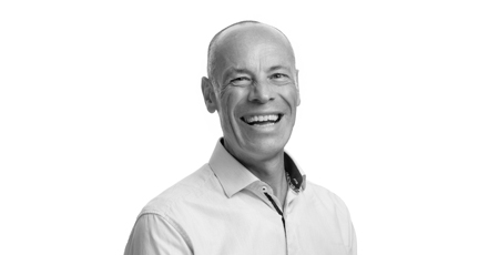 Black-and-white portrait photo of a bald man smiling.