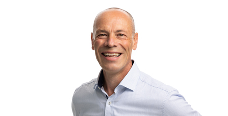 Color portrait photo of a smiling man wearing a light blue shirt.