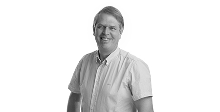 Black-and-white portrait photo of a smiling man, posed at a slight angle with his right shoulder forward.