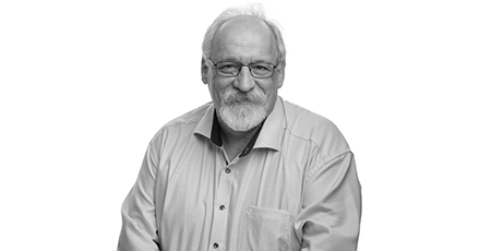 Black-and-white portrait of a person with a beard and glasses, wearing a shirt.